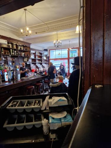 a bar with people sitting at a counter in a room at Aberfoyle Inn in Aberfoyle