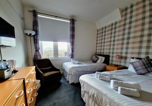 a hotel room with two beds and a chair at Aberfoyle Inn in Aberfoyle
