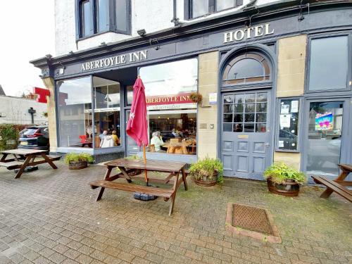 a group of picnic tables in front of a hotel at Aberfoyle Inn in Aberfoyle