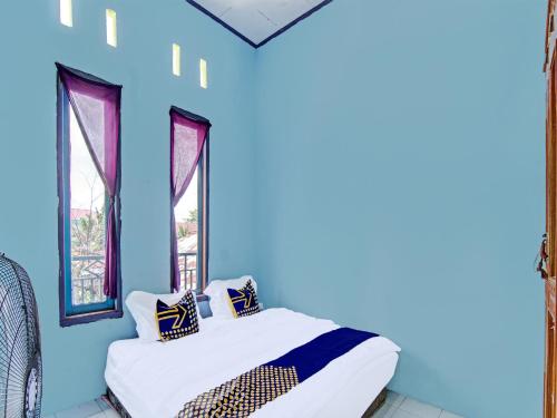 SPOT ON 91918 Najla Guest House Syariah في Parit: غرفة نوم بجدران زرقاء وسرير مع الوسائد