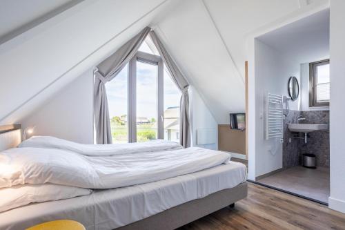 a bedroom with a bed and a large window at Duyndomein Noordwijk in Noordwijk