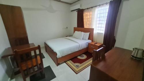 a small bedroom with a bed and a window at Bassi Hotel in Takoradi