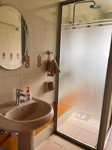 uma casa de banho com um lavatório e um chuveiro em Spacious 3 Bedroom Apartment Excellent Location Bugolobi Kampala - Immersion 1 em Kampala