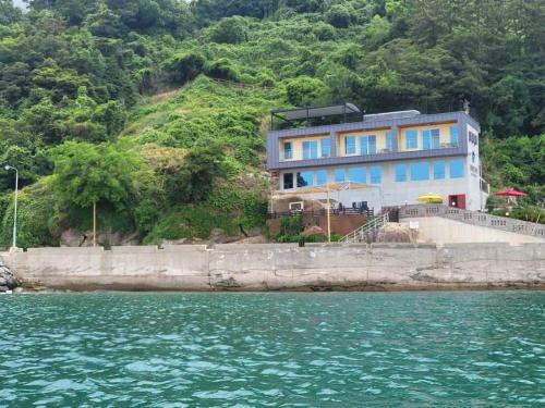 a blue building on a hill next to the water at Somewhales Pension in Namhae