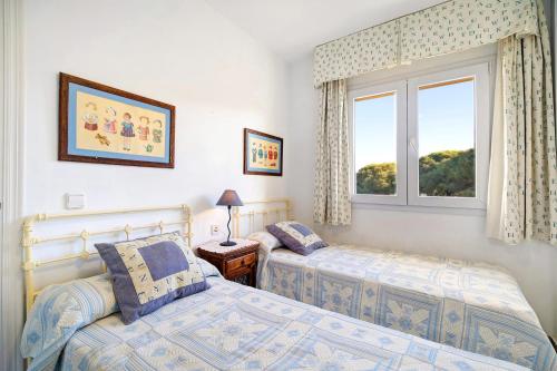 1 dormitorio con 2 camas y ventana en Chalet Cormoran, en Chiclana de la Frontera
