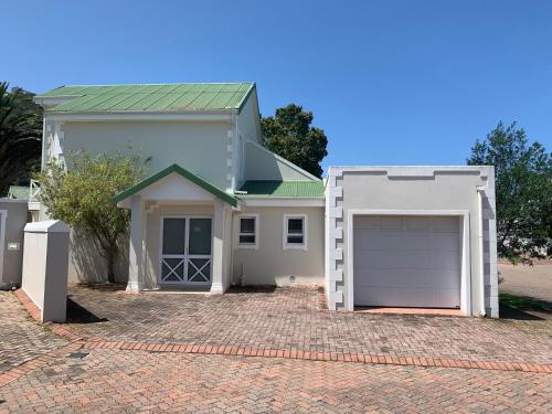 a white house with a garage on a brick driveway at River Club Vacation Home in Plettenberg Bay