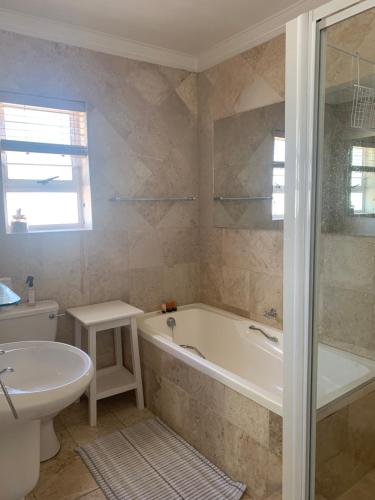 uma casa de banho com uma banheira, um WC e um lavatório. em River Club Vacation Home em Plettenberg Bay