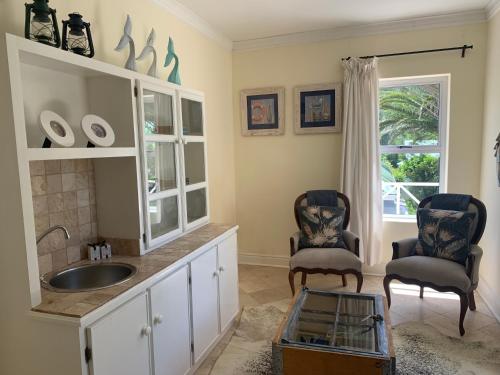 a kitchen with a sink and two chairs at River Club Vacation Home in Plettenberg Bay