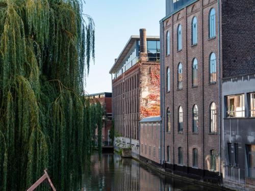 a canal in a city with buildings and a river at Ghent River Hotel in Ghent