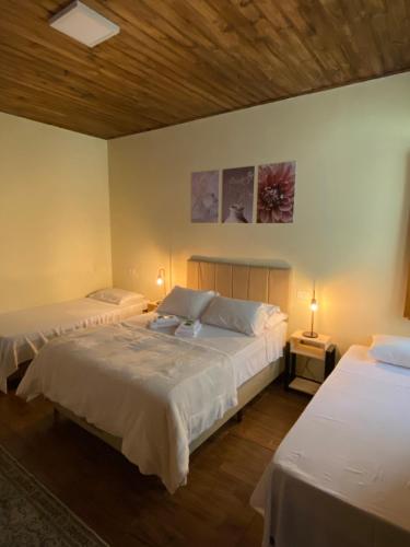 two beds in a room with two lamps on tables at Hospedaria Paiol in São Bento do Sapucaí