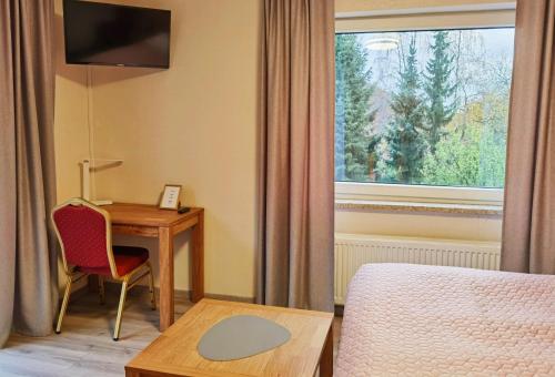 Habitación de hotel con escritorio, cama y ventana en AM BERG Hotel en Herzberg am Harz