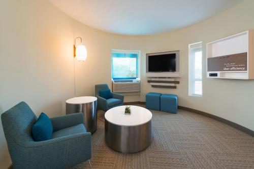 a living room with two chairs and a table and a tv at EVEN Hotel Rockville - Washington, DC Area by IHG in Rockville