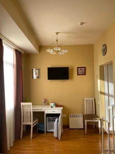 a room with a desk with two chairs and a tv at Fontush Boutique Hotel in Ivano-Frankivsʼk