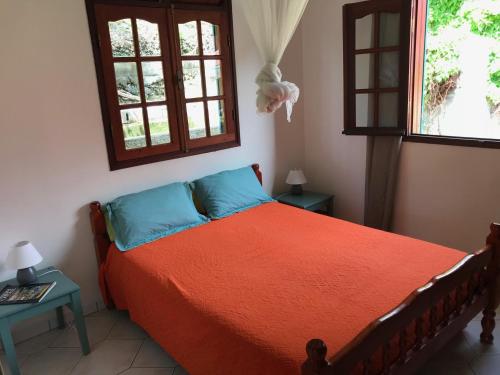 a bedroom with a bed with orange sheets and two windows at Case à Lili, joli haut de villa face à la mer dans le bourg. in Terre-de-Haut