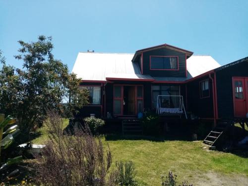 una casa roja y negra con techo blanco en Cycling Hostel Piedra Azul, en Puerto Montt