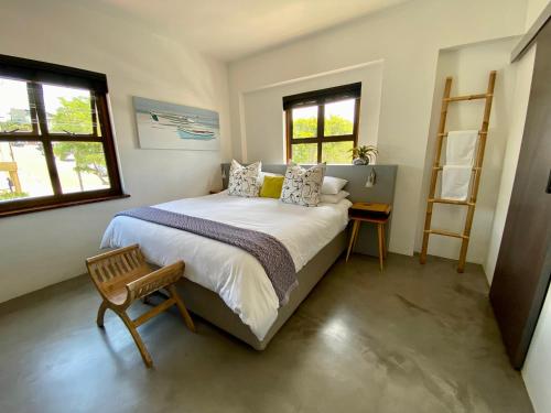 - une chambre avec un grand lit et 2 fenêtres dans l'établissement Stay On Main Plett - Contemporary 2-Bedroom Apartment, à Plettenberg Bay