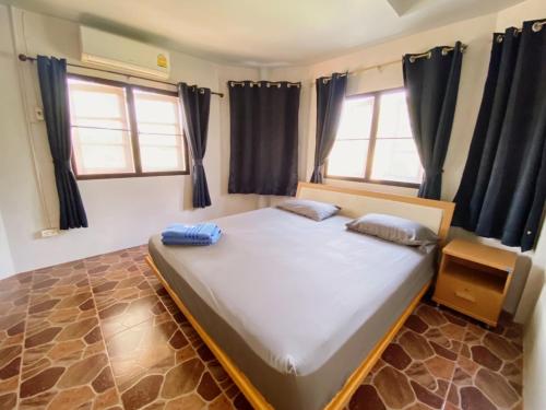 a large bed in a room with two windows at บ้านสวนจันทร์เจ้า in Wang Nam Khieo