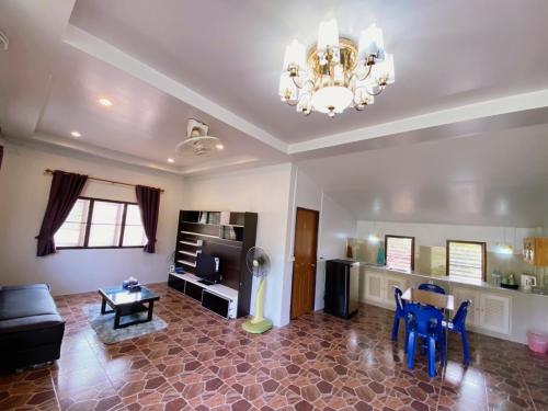 uma sala de estar com um lustre e uma mesa em บ้านสวนจันทร์เจ้า em Wang Nam Khieo