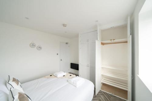 a white bedroom with a bed and a television at Links Loft -2 bed apartment minutes from Aberdeen beach in Aberdeen