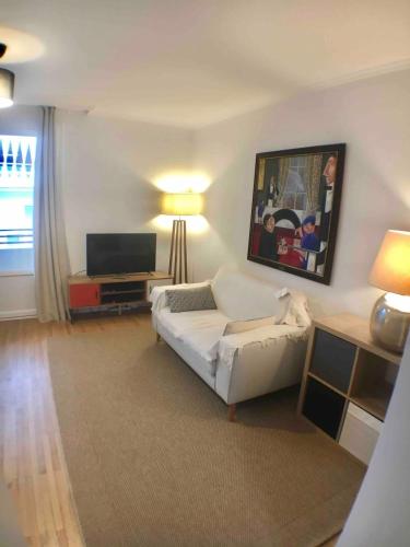 un salon avec un canapé blanc et une télévision dans l'établissement Annecy center 2 steps from the lake Cozy and renovated!, à Annecy