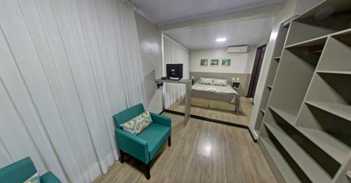 Habitación pequeña con silla azul y cama en Hotel Zata e Flats, en Criciúma
