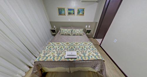 a small bedroom with a bed with a quilt on it at Hotel Zata e Flats in Criciúma