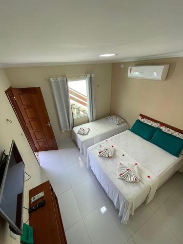 a room with two beds and a television in it at Chalés Paraiso de Pipa in Pipa