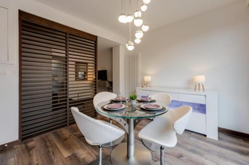 une salle à manger avec une table en verre et des chaises blanches dans l'établissement Studio Suite Annecy - Vue sur le château climatisation, à Annecy