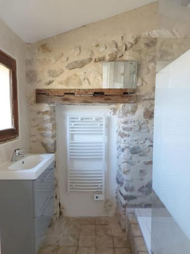 une salle de bain avec un lavabo et un mur en pierre dans l'établissement Charmante Maison avec grand jardin lisière forêt, à Levignen