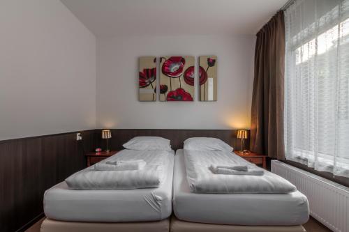 two white beds in a room with a window at Hotel Randenbroek in Amersfoort