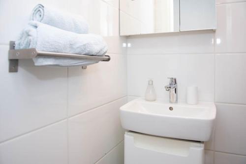 Lovely 2BDR Loft Apartment في سراييفو: حمام أبيض مع حوض ومرآة