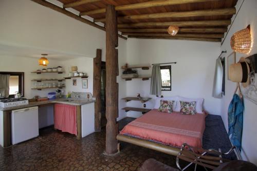 a bedroom with a bed and a kitchen in a room at Pousada Gopak in Praia do Rosa