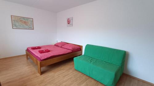 a room with a bed and a green chair at Apartmánek U lanovky in Janske Lazne