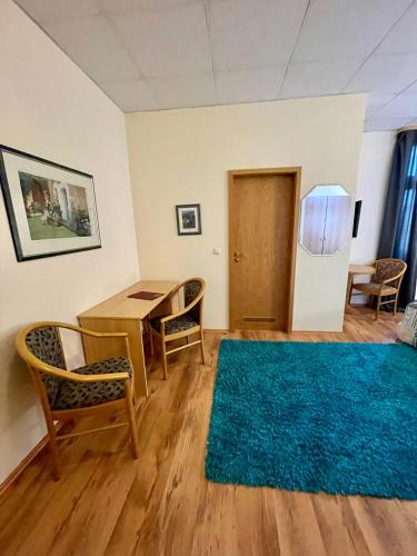 a living room with a table and chairs and a blue rug at Parkhotel Waldschlösschen in Annaberg-Buchholz