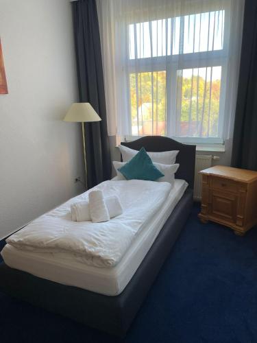 a bedroom with a bed with pillows and a window at Parkhotel Waldschlösschen in Annaberg-Buchholz