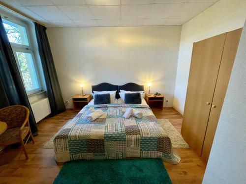 a bedroom with a large bed with two tables and two windows at Parkhotel Waldschlösschen in Annaberg-Buchholz