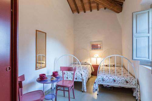 a bedroom with two beds and a table and chairs at Fattoria La Striscia appartamenti in Gambassi Terme