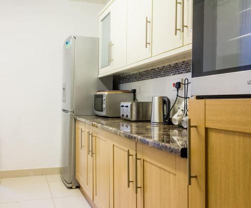 a kitchen with wooden cabinets and a stainless steel refrigerator at Spacious 4 Bed, Parking, Close to Docks in Litherland