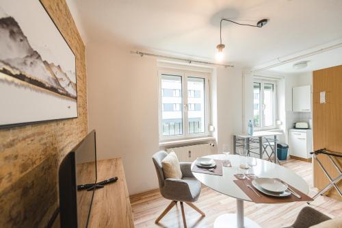 Service Apartment direkt neben Hauptbahnhof Graz في غراتس: غرفة معيشة مع طاولة وكراسي بيضاء