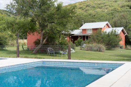a house and a swimming pool in front of a house at Chacra La Invernada Pequeño Hotel de Campo in Villa Giardino