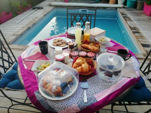 una mesa con comida y bebida junto a una piscina en L'Ecrin d'Azur, en Sanary-sur-Mer