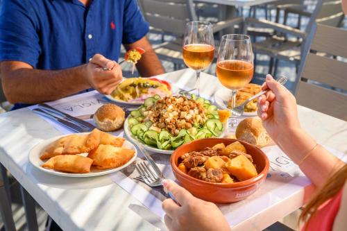 a group of people sitting at a table with food and wine at Vigla Hotel in Aegiali