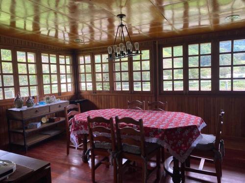 a dining room with a table and chairs and windows at Los Alessandria in Cerro Punta