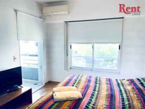 1 dormitorio con 1 cama con una manta colorida y TV en Rent Forest en Buenos Aires