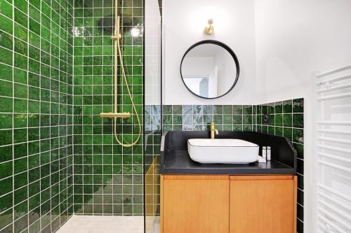 La salle de bains est pourvue de carrelage vert, d'un lavabo et d'une douche. dans l'établissement Superbe Appartement - Père Lachaise, à Paris