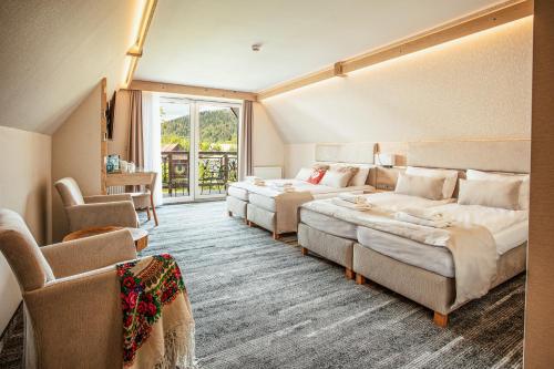 ザコパネにあるVilla Cannes Resort Zakopane - grota solna, sauna fińskaのベッド2台とソファが備わるホテルルームです。