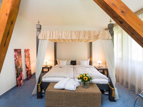 a bedroom with a canopy bed with flowers on a table at Hotel Zur Heidschnucke in Asendorf
