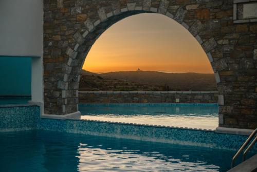 a swimming pool with a view of the sunset through an arch at Vigla Hotel in Aegiali