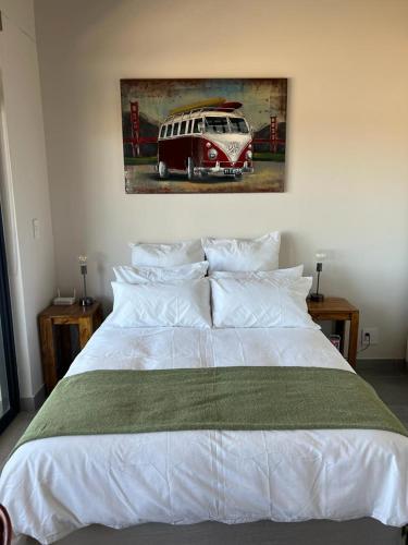 a bedroom with a white bed with a painting on the wall at Kabeljauws Beach Estate in Jeffreys Bay