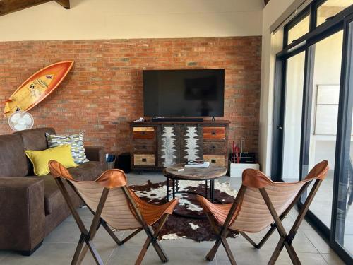 a living room with a couch and a tv and chairs at Kabeljauws Beach Estate in Jeffreys Bay